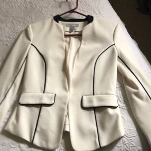 Short cream colored blazer; black piping.